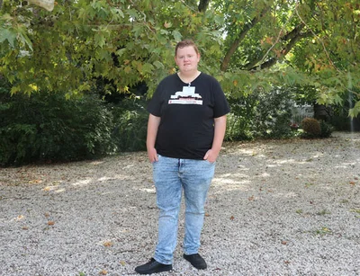 Portret van jongerenambassadeur Melvin ten voeten uit. Hij draagt een zwart T-shirt en een spijkerbroek.