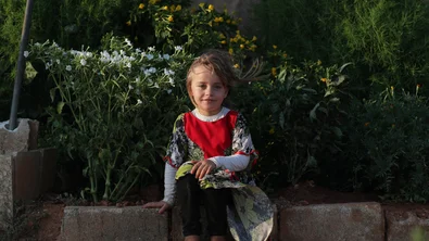 CH1731800-Abeer-6-sitting-in-front-of-her-family-s-small-garden-that-s-next-to-their-tent-at-the-displacement-camp-where-they-re-living-in-Syria.JPG