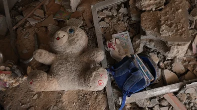CH1909346-A-child-s-school-backpack-and-a-doll-among-a-rubble-in-Gaza-LR