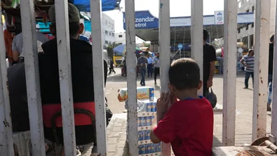 Een kind staat achter een hek in Gaza