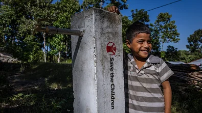 Fatra staat bij een kraan, aangelegd door Save the Children in Indonesië
