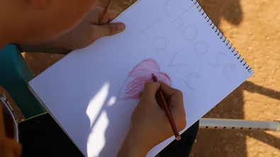 De vijftienjarige Saleh maakt een tekening met de woorden 'choose love'