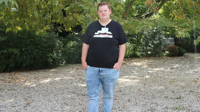 Portret van jongerenambassadeur Melvin ten voeten uit. Hij draagt een zwart T-shirt en een spijkerbroek.