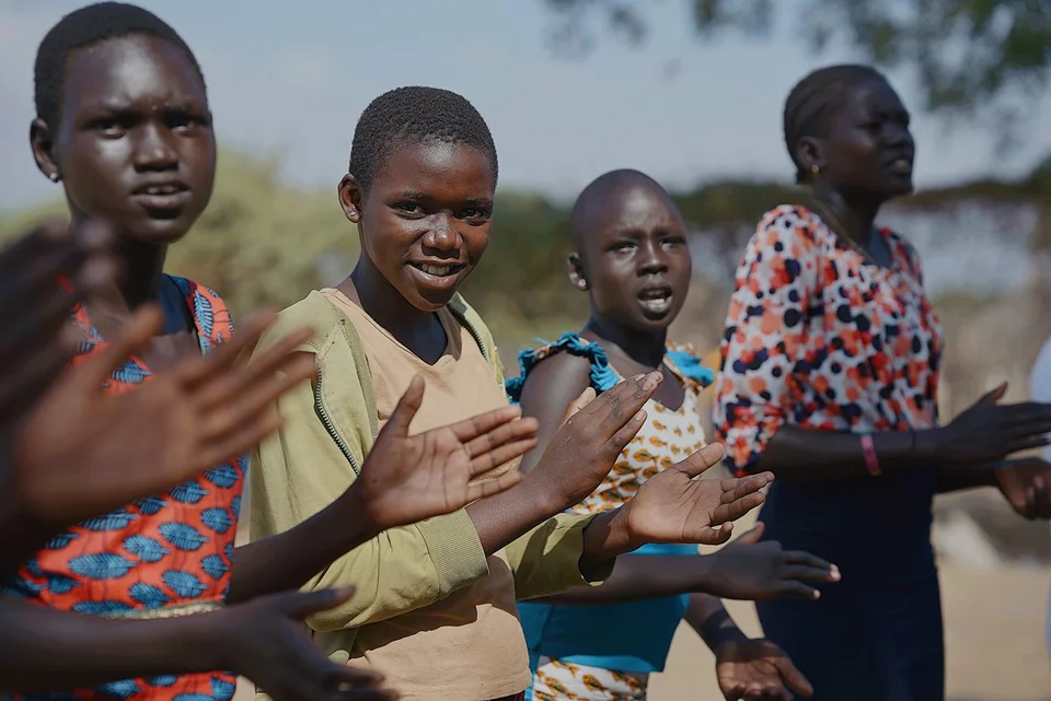 Vijf west-afrikaanse kinderen staan naast elkaar klappen in hun handen