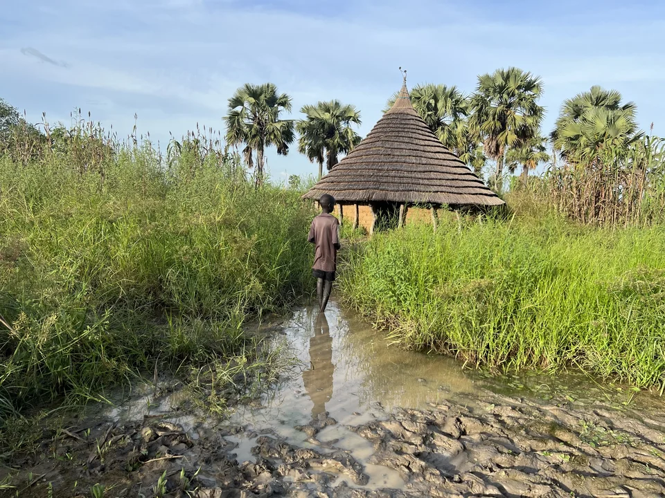 A young boy standing in front of a flooded house