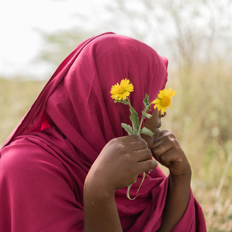 Asma poseert met een bloem voor haar gezicht