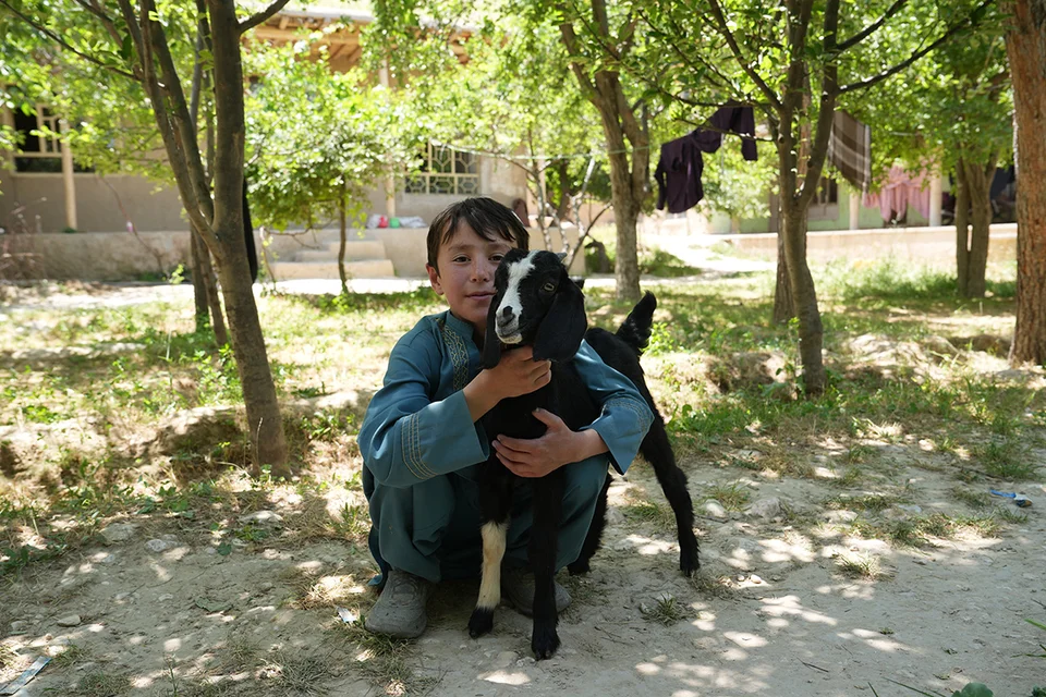 De elfjarige Jawid poseert mijn zijn geitje voor zijn huis in Afghanistan