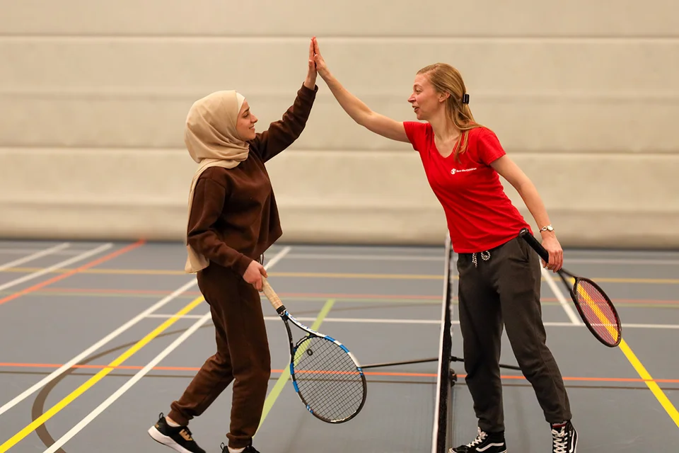 Een deelnemer van de sportcarrousel geeft een high five aan een medewerker