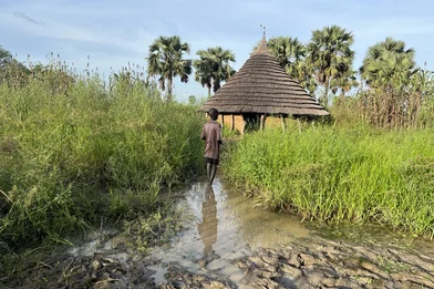 A young boy standing in front of a flooded house