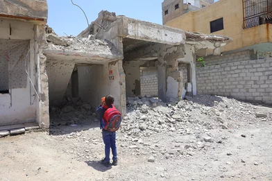 De zevenjarige Issa staat voor zijn gebombardeerde school in Raqqa, Syrië, waar hij woont