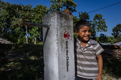 Fatra staat bij een kraan, aangelegd door Save the Children in Indonesië