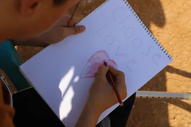 De vijftienjarige Saleh maakt een tekening met de woorden 'choose love'