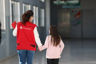 Save the Children medewerker loopt meer een meisje door een school in Libanon