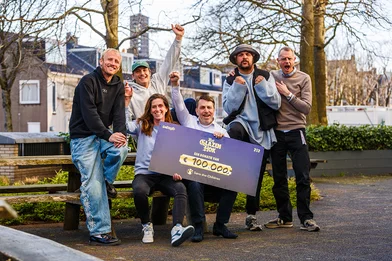 De leden van Goldband en medewerkers van Save the Children met een cheque van 100.000 euro