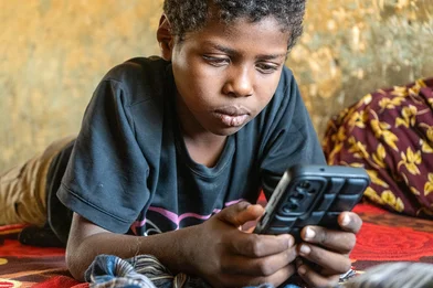 Een jongen zit op zijn telefoon