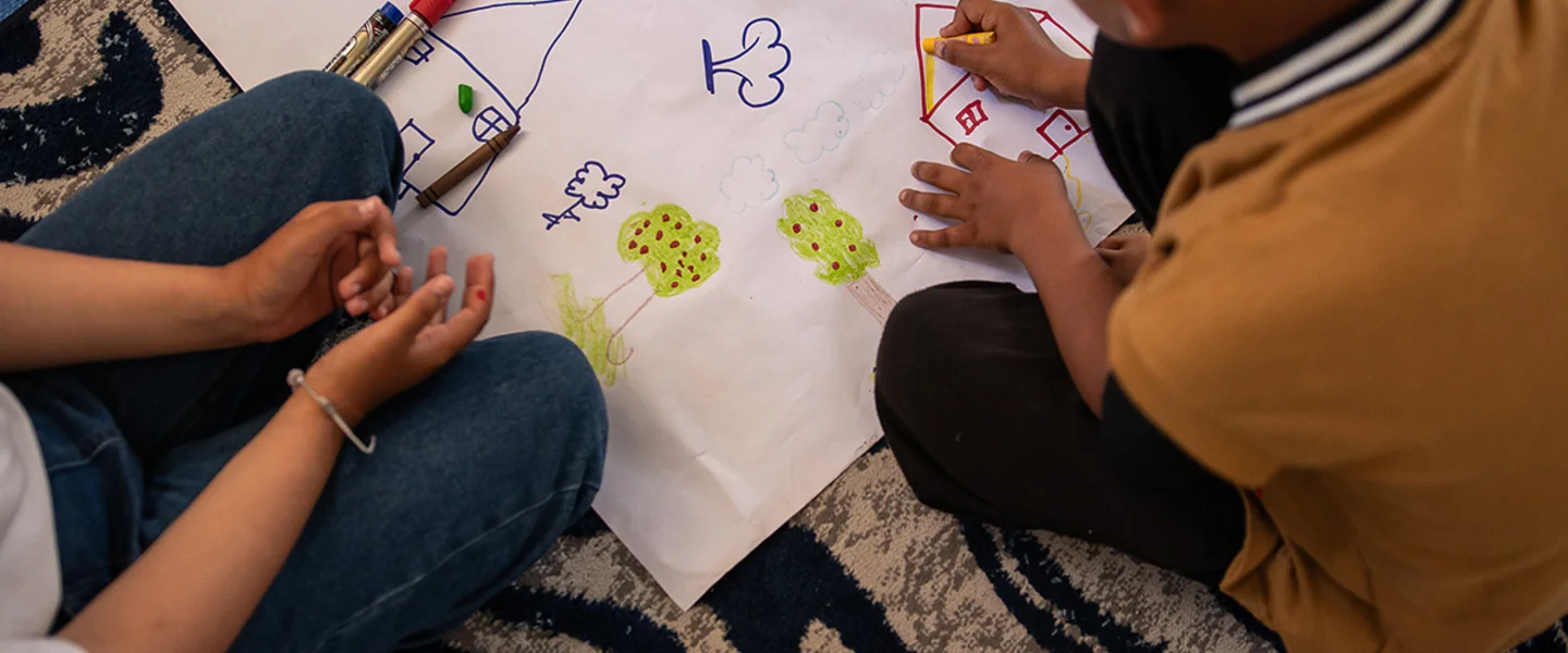 Shadi en zijn nicht Aya tekenen in een leerplek van Save the Children