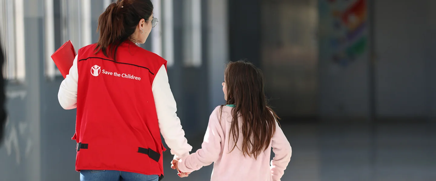 Save the Children medewerker loopt meer een meisje door een school in Libanon
