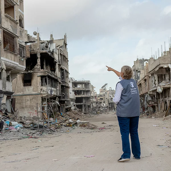 Medewerker van Save the Children wijst naar vernielde gebouwen in Gaza