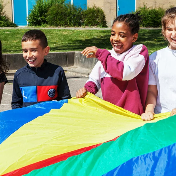 kinderen spelen buiten met een groot rond doek
