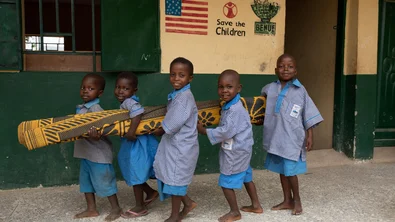 ch1681457-children-carry-a-mat-to-their-classroom-at-their-school-in-benue-state-nigeria-min