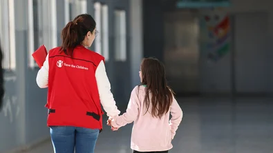 Save the Children medewerker loopt meer een meisje door een school in Libanon