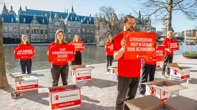Medewerkers van Save the Children staan met borden voor de hofvijver in Den Haag