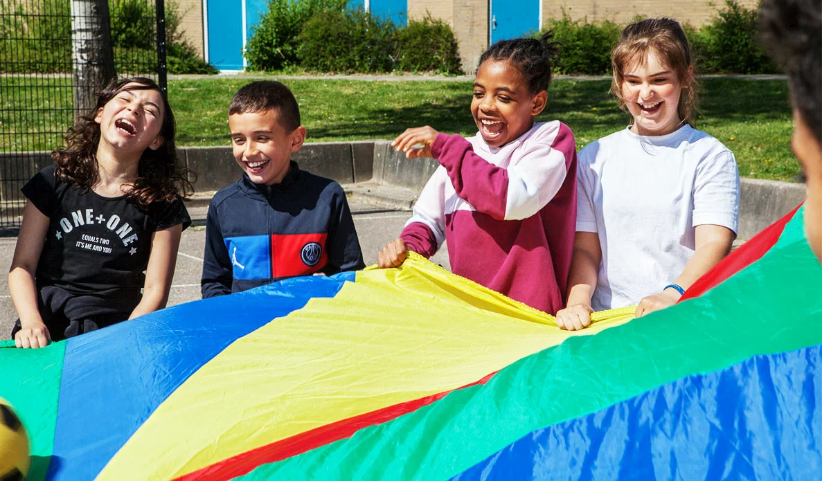 kinderen spelen buiten met een groot rond doek