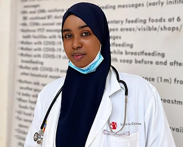 Somalische gezondheidswerker, ze draagt een witte jas met het Save the Children logo en een stethoscoop om haar nek.