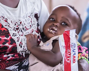 Baby in de armen van zijn of haar moeder. Ze heeft de baby net noodvoeding gegeven.