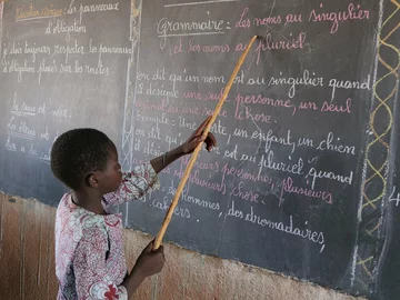 CH1545245-Souleymane-aged-14-points-to-words-on-a-blackboard-at-school-Yatenga-province-Burkina-Faso