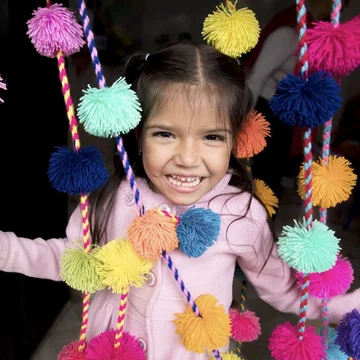 Meisje staat blij tussen slingers met pompoms