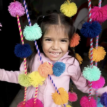 Meisje staat blij tussen slingers met pompoms