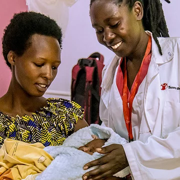 Moeder met haar baby in haar armen, een verloskundige staat naast ze