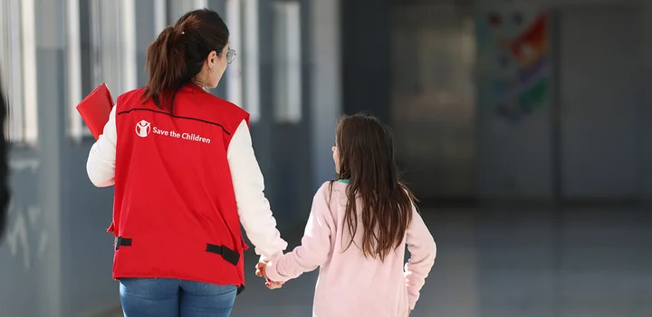 Save the Children medewerker loopt meer een meisje door een school in Libanon